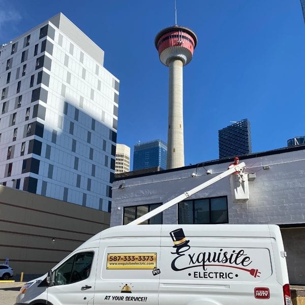 Exquisite-Electric-Commercial-Electrical-Contractors-Bucket-Truck-and-Van Image of Exquisite Electric Commercial Electrical Contractors Fixing a Light With a Bucket Truck and Van